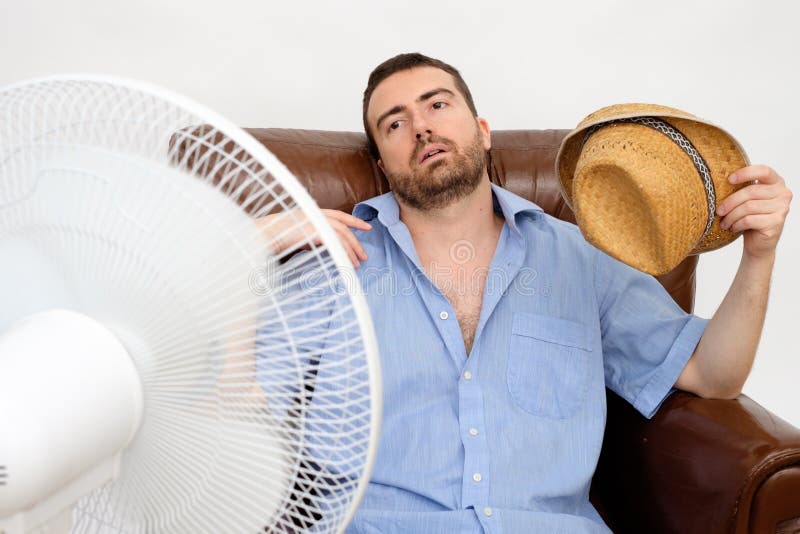 Flushed man feeling hot in front of a fan. Flushed man feeling hot in front of a fan