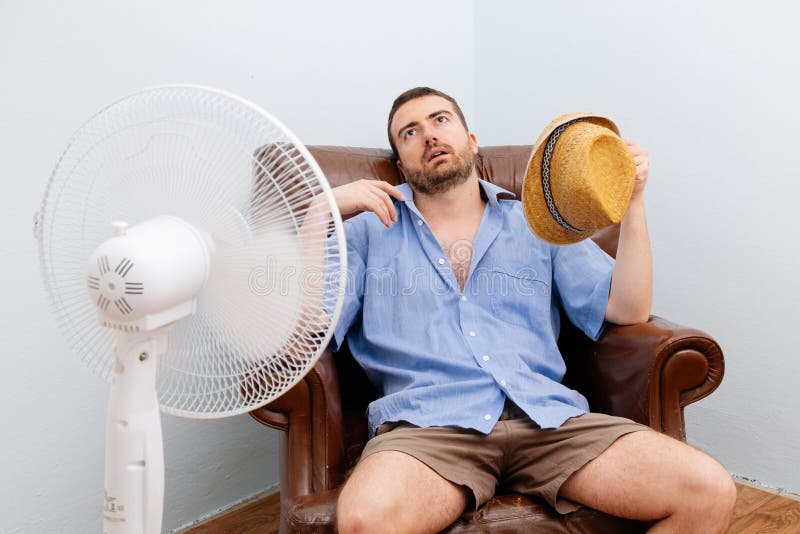 Flushed man feeling hot in front of a fan. Flushed man feeling hot in front of a fan