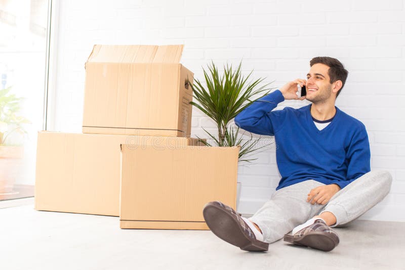 Homem no apartamento com telefone móvel e móvel foto de stock