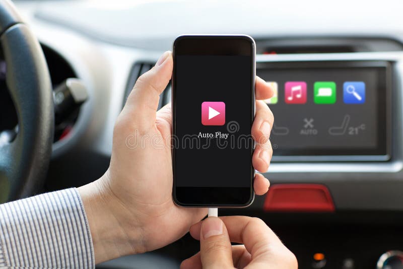 Man hand in car holding phone with app Auto Play on the screen and on multimedia system. Man hand in car holding phone with app Auto Play on the screen and on multimedia system