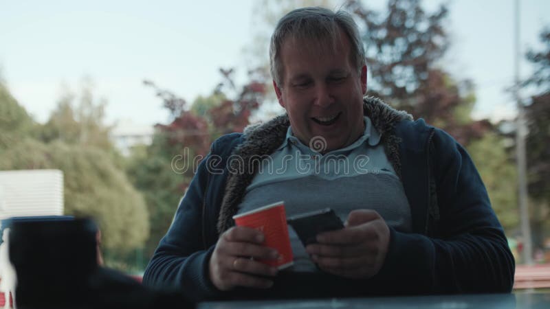 Homem no t-shirt com Internet de papel dos surches da xícara de café em seu smartphone