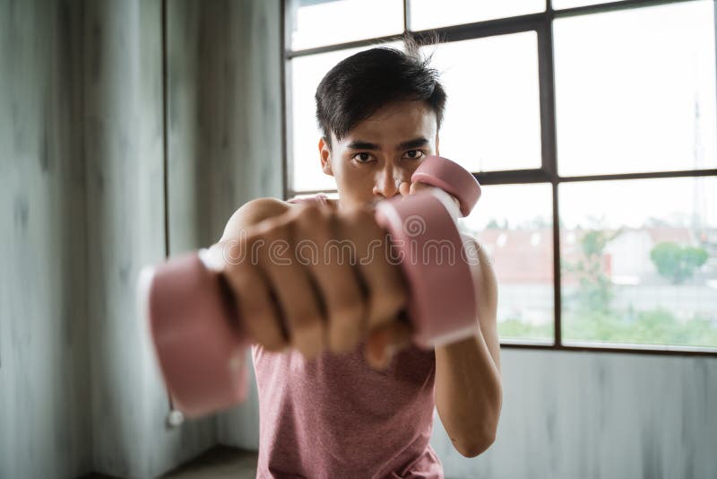 Homem novo asiático com o peso que faz o exercício do peso foto de stock Homem novo asiático com o peso que faz o exercício do peso foto de stock