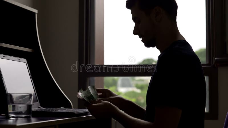 Homem novo bem sucedido que conta o dinheiro, silhueta do orçamento do planeamento do estudante foto de stock Homem novo bem sucedido que conta o dinheiro, silhueta do orçamento do planeamento do estudante foto de stock