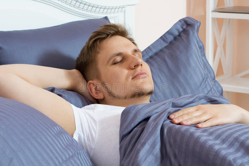 Homem novo bonito que dorme na cama na manhã foto de stock Homem novo bonito que dorme na cama na manhã foto de stock