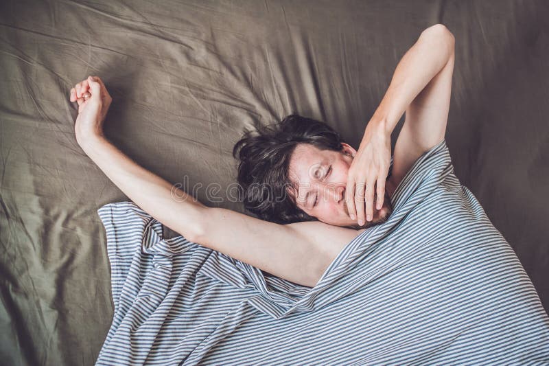 Homem novo bonito que encontra-se para baixo na cama e que dorme, vista superior Não obtenha bastante conceito do sono fotografia de stock Homem novo bonito que encontra-se para baixo na cama e que dorme, vista superior Não obtenha bastante conceito do sono fotografia de stock