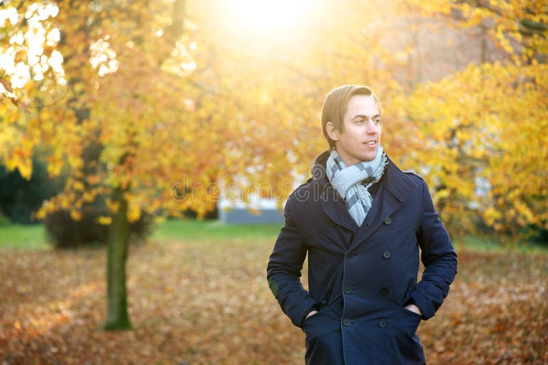 Homem novo bonito que levanta fora em um dia do outono imagem de stock royalty free Homem novo bonito que levanta fora em um dia do outono imagem de stock royalty free