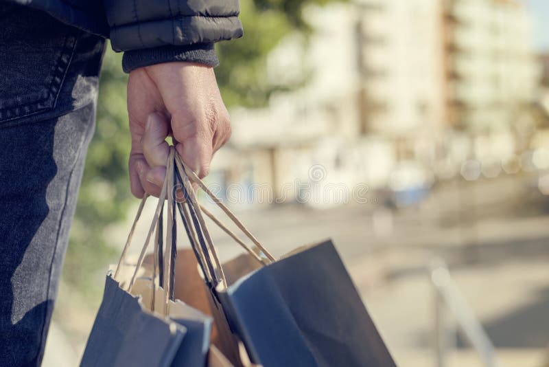 Homem novo com alguns sacos de compras na rua foto de stock Homem novo com alguns sacos de compras na rua foto de stock
