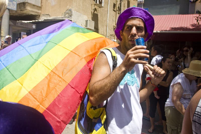 Homem novo com a bandeira do arco-íris na parada Ta do orgulho fotografia de stock Homem novo com a bandeira do arco-íris na parada Ta do orgulho fotografia de stock
