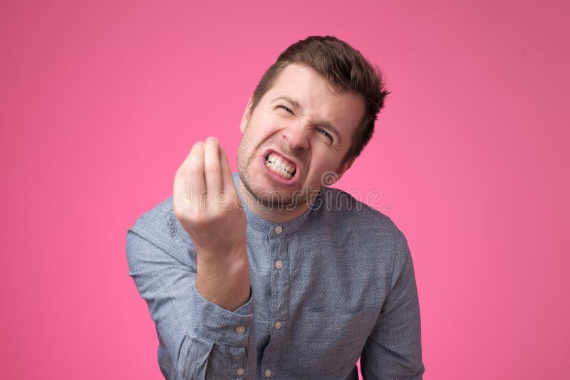 Homem novo considerável que olha irritado mostrando o gesto do italiano sobre o fundo cor-de-rosa fotos de stock royalty free Homem novo considerável que olha irritado mostrando o gesto do italiano sobre o fundo cor-de-rosa fotos de stock royalty free