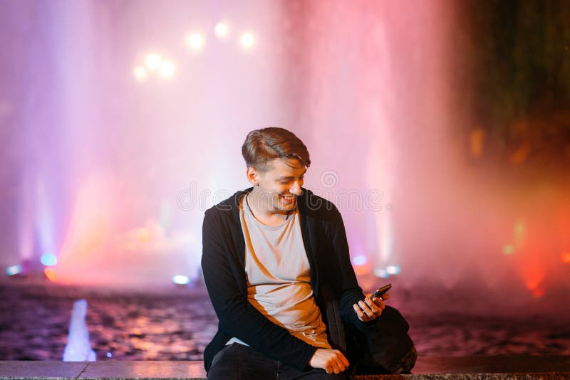 Homem novo considerável que usa o smartphone na cidade imagem de stock royalty free Homem novo considerável que usa o smartphone na cidade imagem de stock royalty free