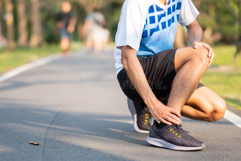 Homem novo da aptidão que guarda seu ferimento de pé dos esportes músculo doloroso durante o treinamento Corredor asiático que te fotografia de stock royalty free Homem novo da aptidão que guarda seu ferimento de pé dos esportes músculo doloroso durante o treinamento Corredor asiático que te fotografia de stock royalty free