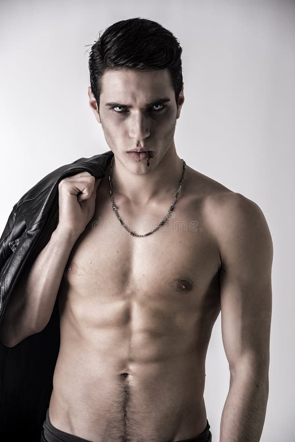 Homem novo do vampiro com o casaco de cabedal preto no ombro imagens de stock Homem novo do vampiro com o casaco de cabedal preto no ombro imagens de stock