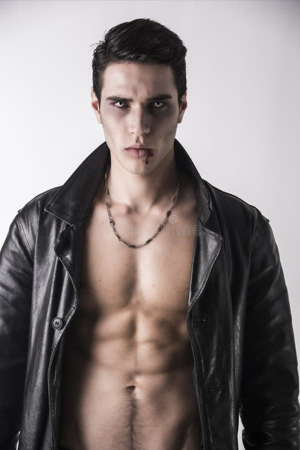 Homem novo do vampiro em um casaco de cabedal preto aberto, mostrando seus caixa e Abs fotos de stock Homem novo do vampiro em um casaco de cabedal preto aberto, mostrando seus caixa e Abs fotos de stock