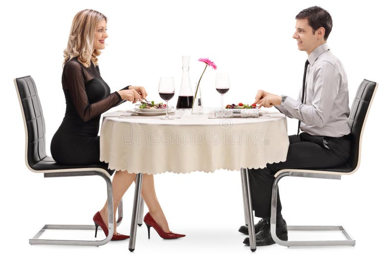 Homem novo e mulher que comem em uma data foto de stock Homem novo e mulher que comem em uma data foto de stock