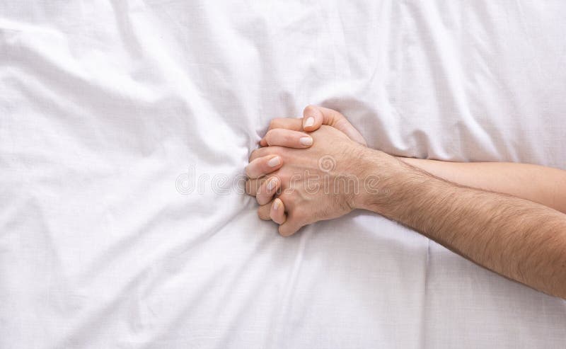 Homem novo e mãos fêmeas na cama, close up fotos de stock Homem novo e mãos fêmeas na cama, close up fotos de stock