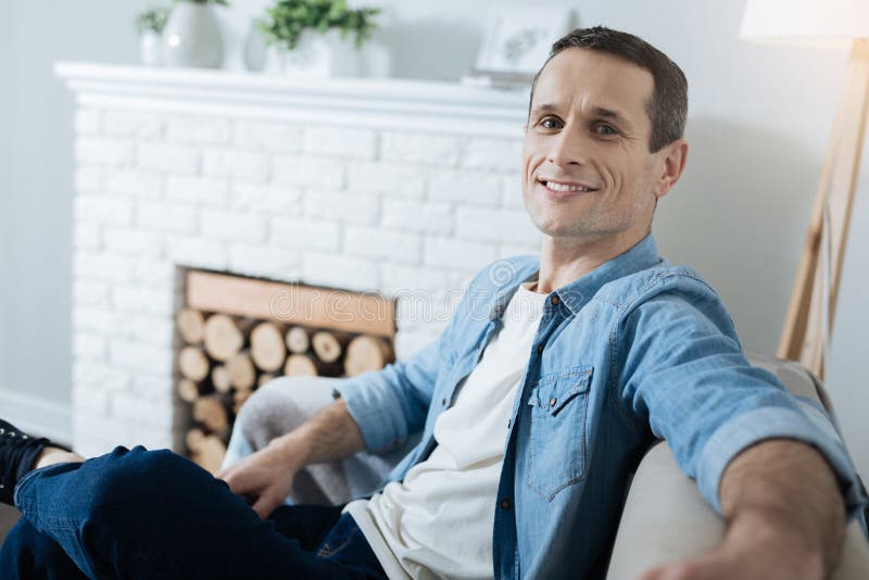 Homem novo feliz que relaxa no sofá imagens de stock Homem novo feliz que relaxa no sofá imagens de stock