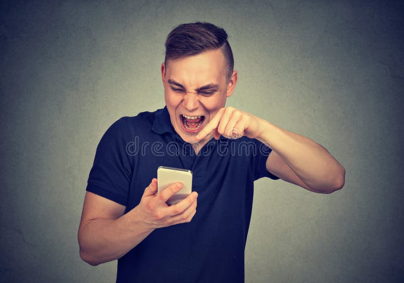 Homem novo irritado que grita no telefone celular fotografia de stock Homem novo irritado que grita no telefone celular fotografia de stock