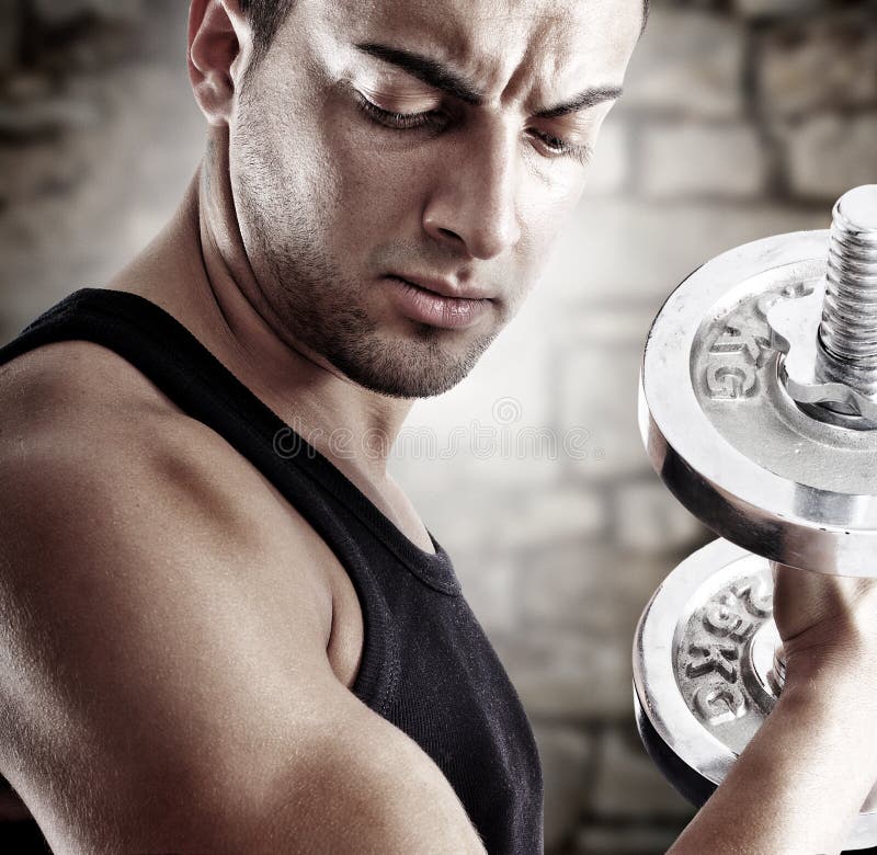 Young man doing weights lifting on stone background. Young man doing weights lifting on stone background