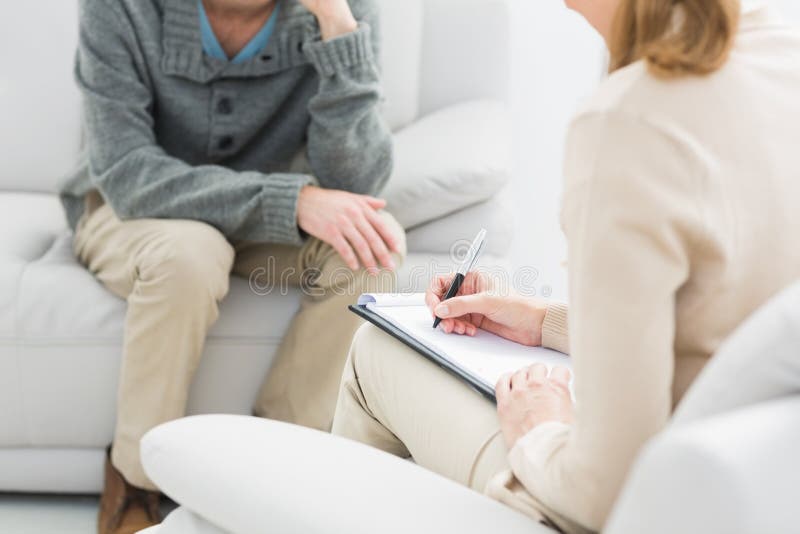 Homem novo na reunião com um psicólogo imagem de stock Homem novo na reunião com um psicólogo imagem de stock