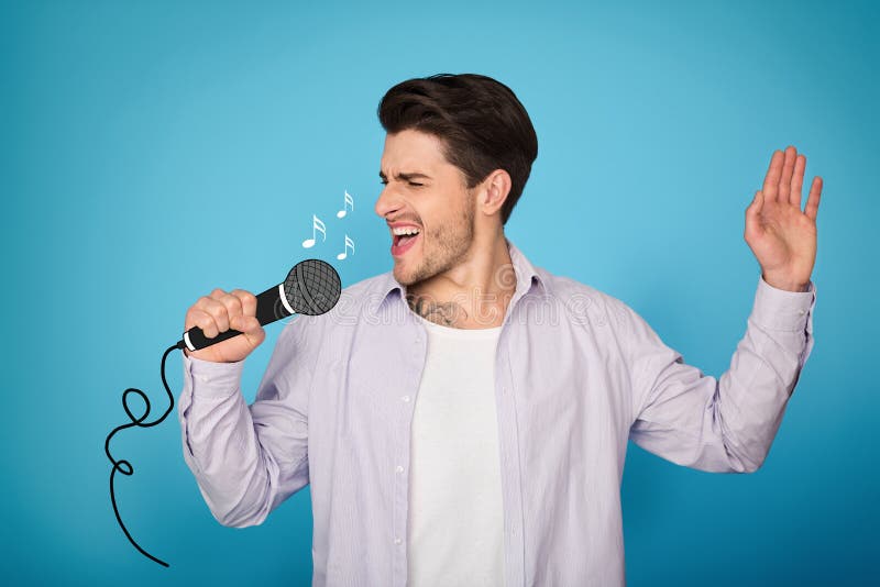 Homem novo que canta ruidosamente contra o fundo azul fotografia de stock royalty free Homem novo que canta ruidosamente contra o fundo azul fotografia de stock royalty free
