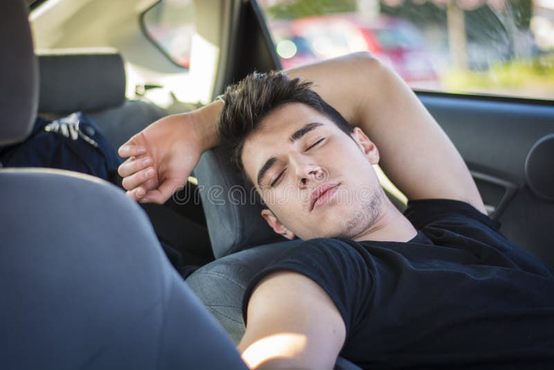 Homem novo que dorme dentro de seu carro, esgotado imagens de stock Homem novo que dorme dentro de seu carro, esgotado imagens de stock
