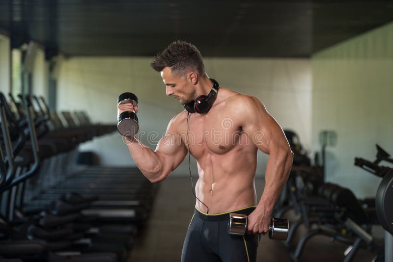 Homem novo que faz o exercício para o bíceps com pesos imagens de stock Homem novo que faz o exercício para o bíceps com pesos imagens de stock