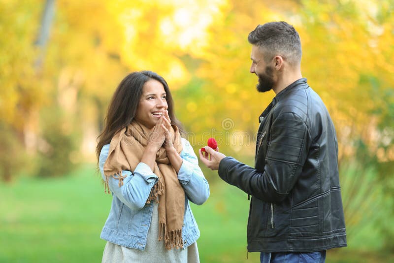 Homem novo que propõe ao seu amado no parque do outono fotografia de stock royalty free Homem novo que propõe ao seu amado no parque do outono fotografia de stock royalty free