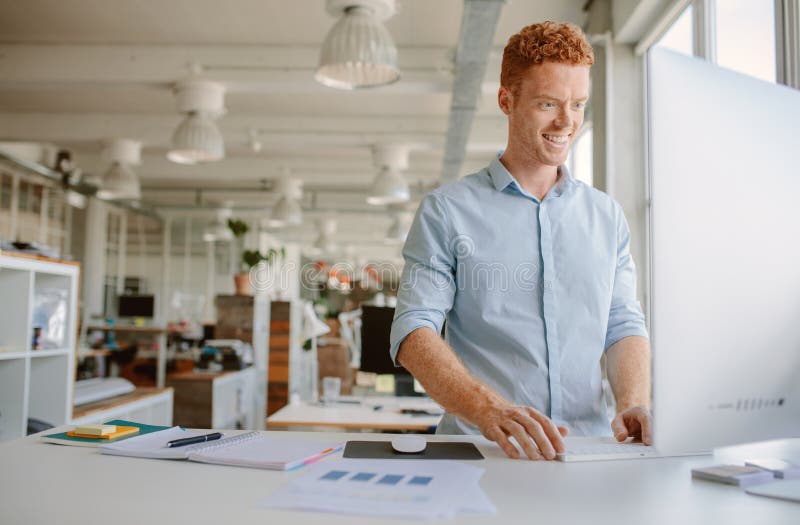 Homem novo que trabalha no escritório moderno imagem de stock Homem novo que trabalha no escritório moderno imagem de stock