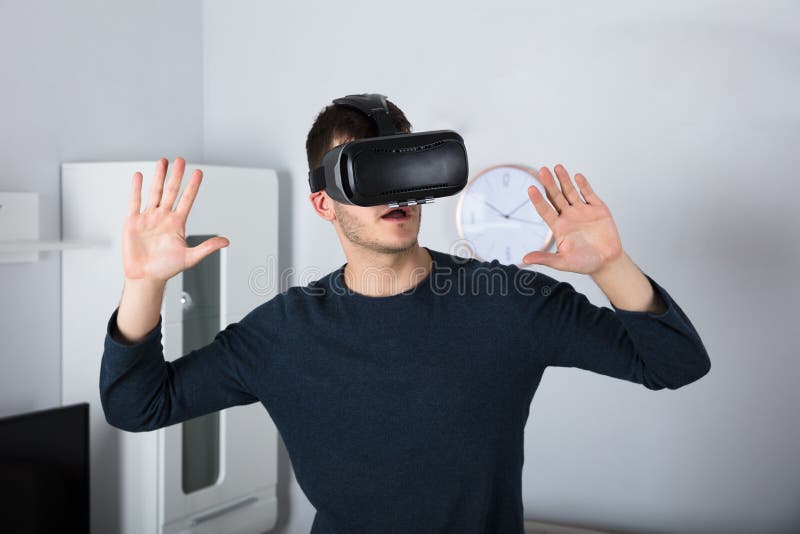 Homem novo que usa auriculares da realidade virtual foto de stock Homem novo que usa auriculares da realidade virtual foto de stock