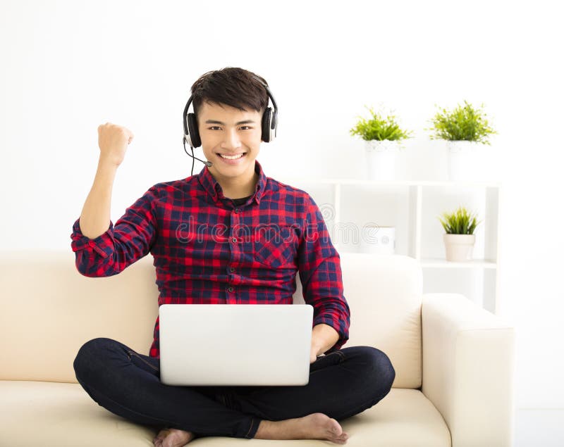 homem novo que usa o laptop com auriculares imagem de stock homem novo que usa o laptop com auriculares imagem de stock