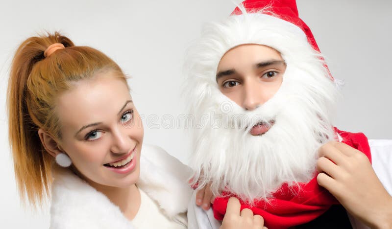 Homem novo vestido como Santa Clause para o Natal e a mulher no branco foto de stock royalty free Homem novo vestido como Santa Clause para o Natal e a mulher no branco foto de stock royalty free
