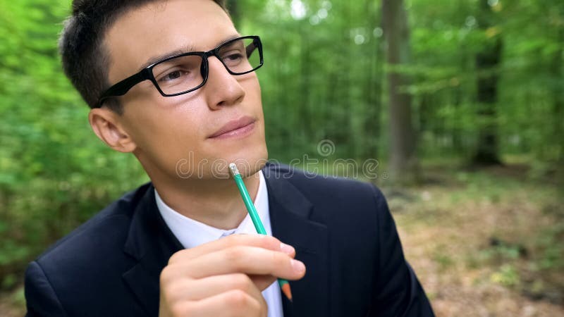 Homem pensativo que pensa sobre a ideia eco-amigável nova do começo acima, sentando-se na floresta imagens de stock Homem pensativo que pensa sobre a ideia eco-amigável nova do começo acima, sentando-se na floresta imagens de stock