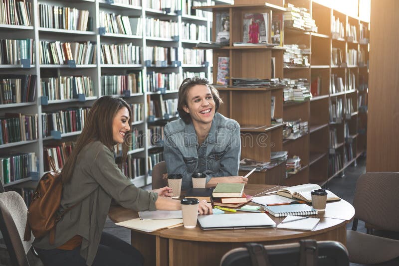 Homem positivo e menina que estudam no ateneu imagem de stock Homem positivo e menina que estudam no ateneu imagem de stock