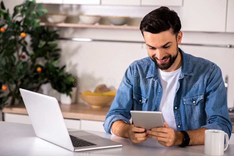 Homem positivo que usa sua tabuleta imagens de stock Homem positivo que usa sua tabuleta imagens de stock