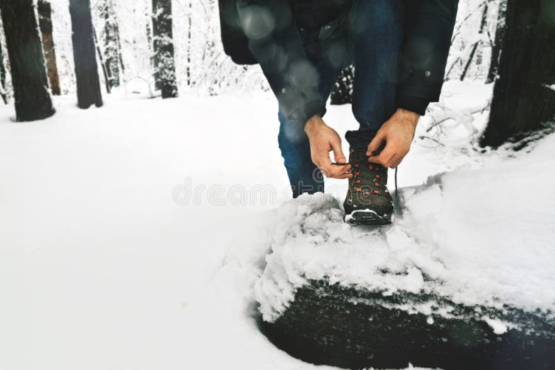 Homem que amarra o estilo de vida nevado da floresta do inverno das botas dos laços fotografia de stock Homem que amarra o estilo de vida nevado da floresta do inverno das botas dos laços fotografia de stock