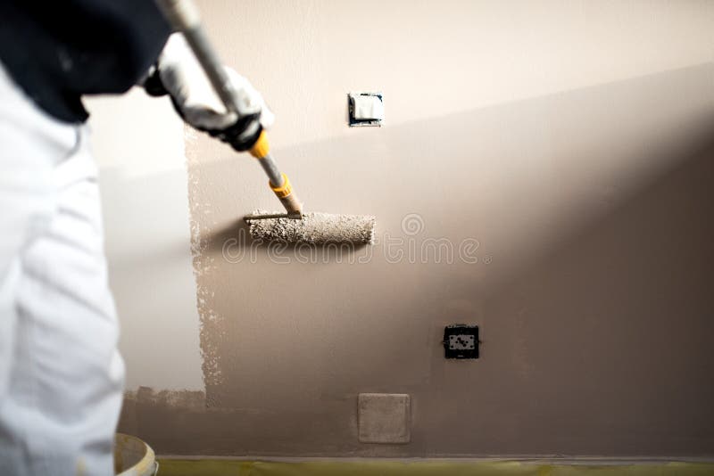 Homem que decora paredes com pintura Pintura do trabalhador do emplastro da construção e renovação com ferramentas profissionais