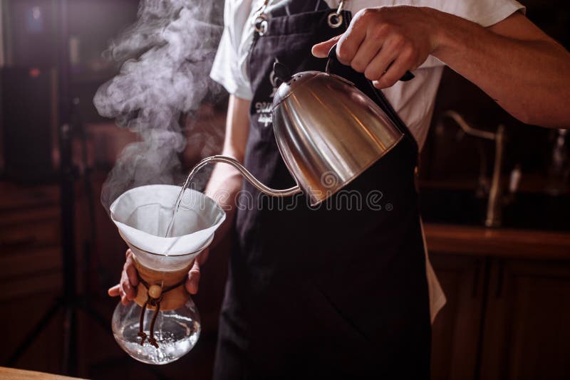 Homem que derrama a água quente para fazer o café fotografia de stock royalty free Homem que derrama a água quente para fazer o café fotografia de stock royalty free