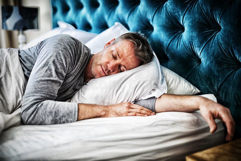Homem que dorme na cama no quarto imagens de stock royalty free Homem que dorme na cama no quarto imagens de stock royalty free