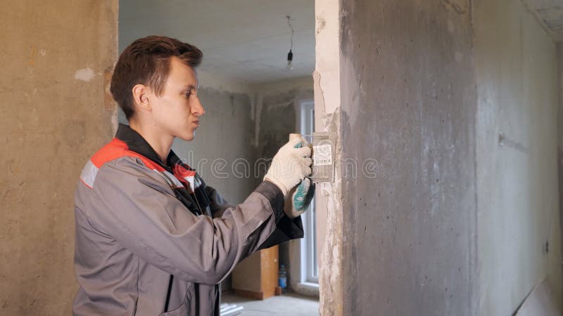 Homem que emplastra o muro de cimento no apartamento