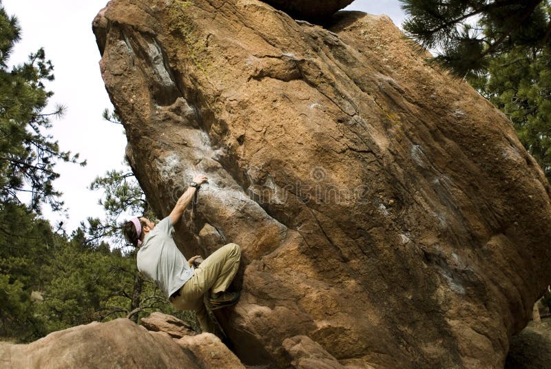 Young man climbing boulder outcropping. Young man climbing boulder outcropping.