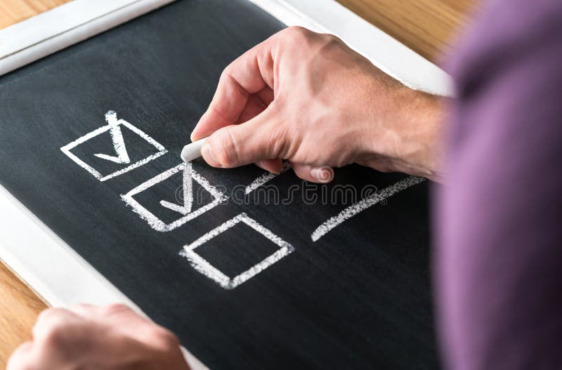 Homem que escreve o sinal à lista de verificação no quadro-negro Documento do trabalho terminado e de tarefas terminadas no quadr fotografia de stock royalty free Homem que escreve o sinal à lista de verificação no quadro-negro Documento do trabalho terminado e de tarefas terminadas no quadr fotografia de stock royalty free