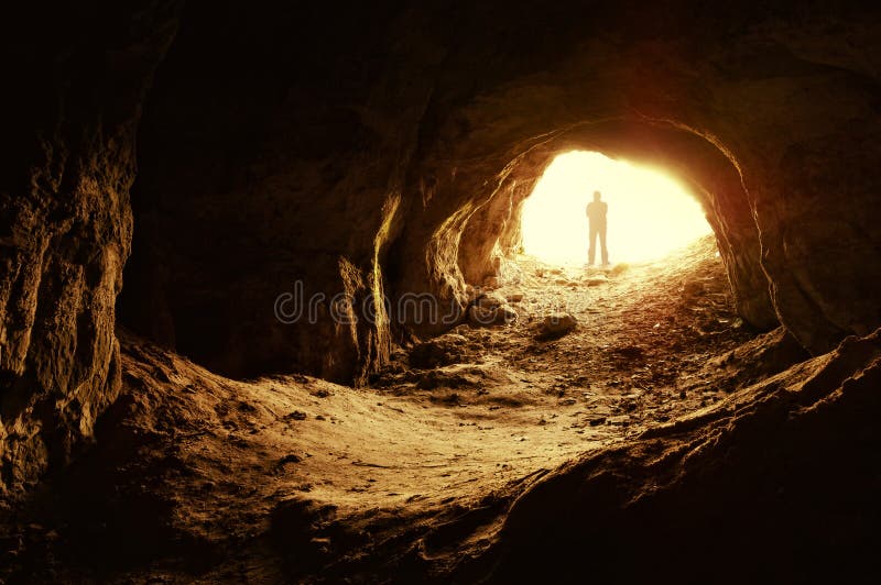 Homem que está na frente de uma entrada da caverna