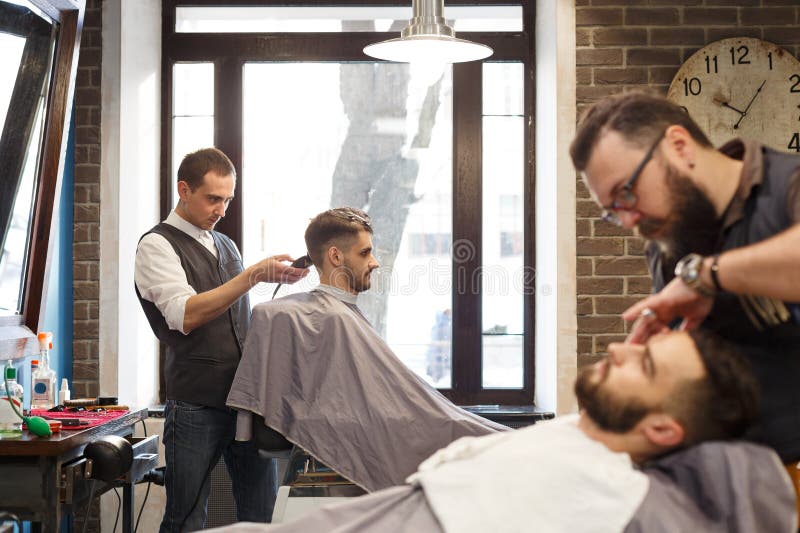 Homem que obtém o corte de cabelo pelo barbeiro no barbeiro imagens de stock royalty free Homem que obtém o corte de cabelo pelo barbeiro no barbeiro imagens de stock royalty free