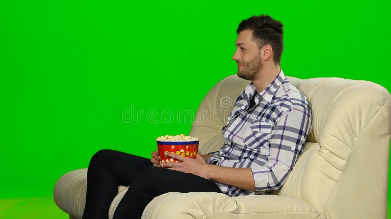 Jovem macho comendo batata frita assistindo filme na superfície branca