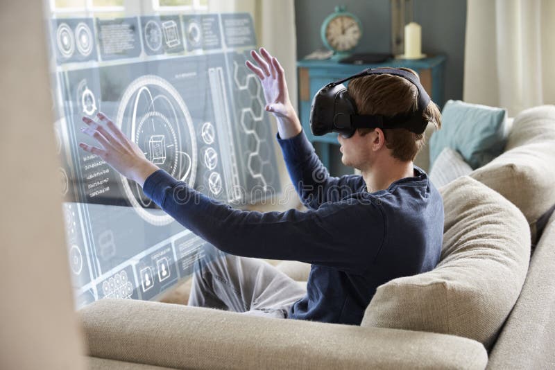 Homem que senta-se em auriculares da realidade de Sofa At Home Wearing Virtual foto de stock Homem que senta-se em auriculares da realidade de Sofa At Home Wearing Virtual foto de stock