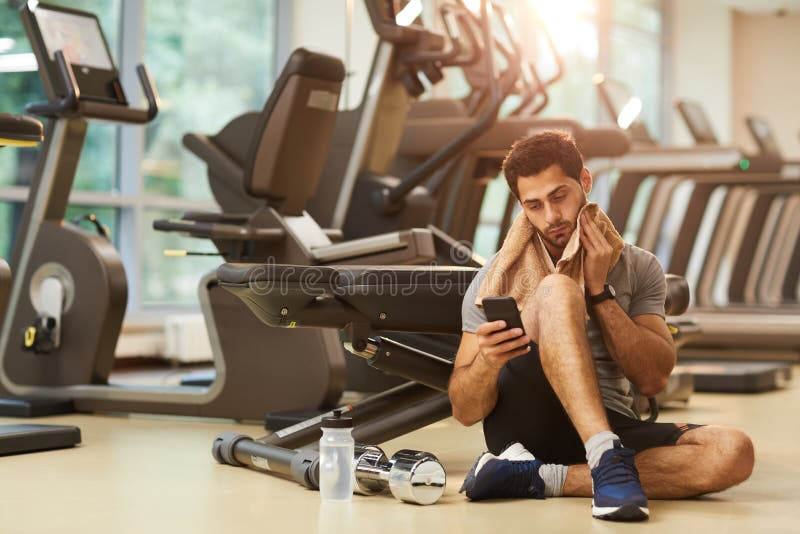 Homem que senta-se no assoalho no Gym foto de stock Homem que senta-se no assoalho no Gym foto de stock