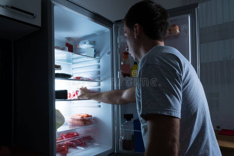 Homem que toma o alimento do refrigerador foto de stock royalty free Homem que toma o alimento do refrigerador foto de stock royalty free