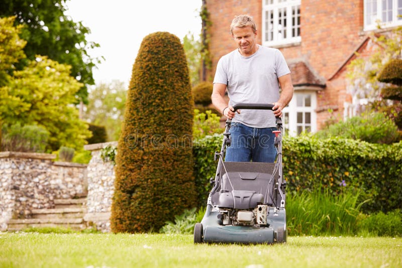 Homem que trabalha na grama do corte do jardim com cortador de grama fotos de stock Homem que trabalha na grama do corte do jardim com cortador de grama fotos de stock