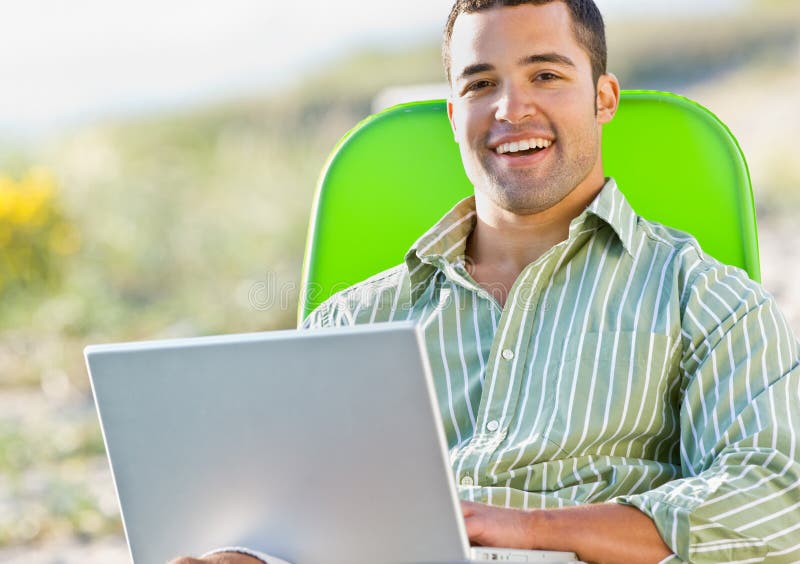Homem que usa o portátil na praia imagens de stock royalty free Homem que usa o portátil na praia imagens de stock royalty free