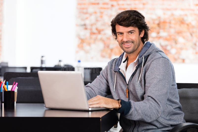 Homem que usa o sorriso ocasional do homem de negócios do portátil foto de stock Homem que usa o sorriso ocasional do homem de negócios do portátil foto de stock